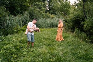 A playful outdoor photoshoot in a green meadow with orange and white clothing.
