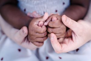 Close up shot of holding hands against a light colored fabric background.