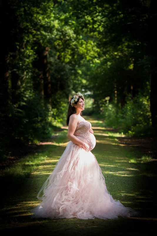 foto van een zwangere dame in kleding van fotograaf tijdens een fotoreportage in het bos