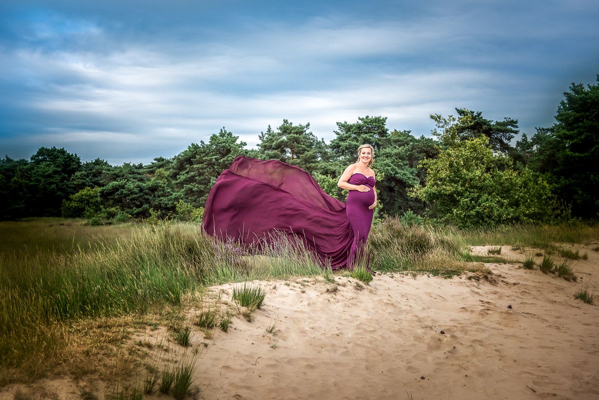 Zwangerschapskleed met sleep tijdens fotoreportage van zwangere dame
