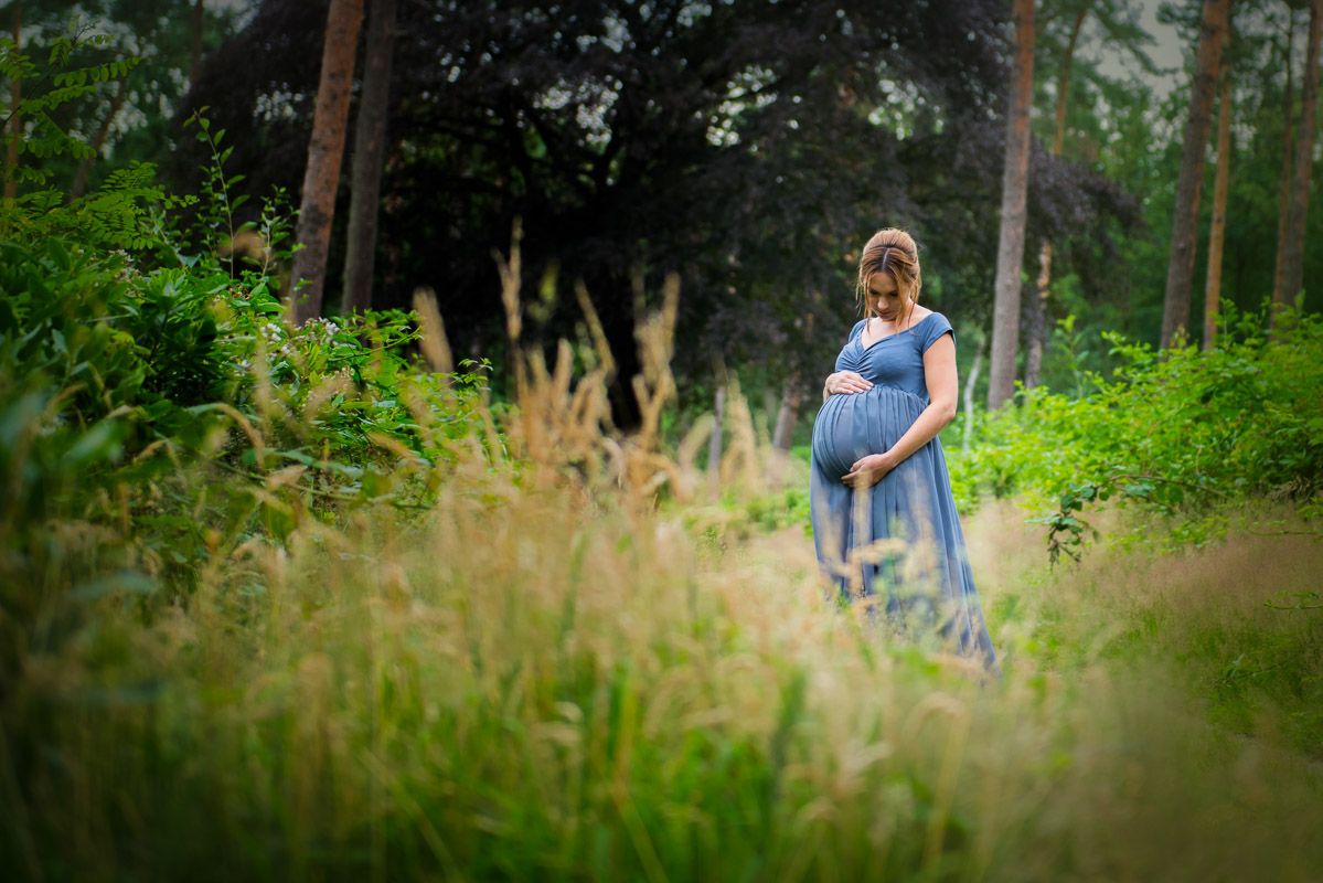zwangere vrouw in het lange gras tijdens een fotoreportage