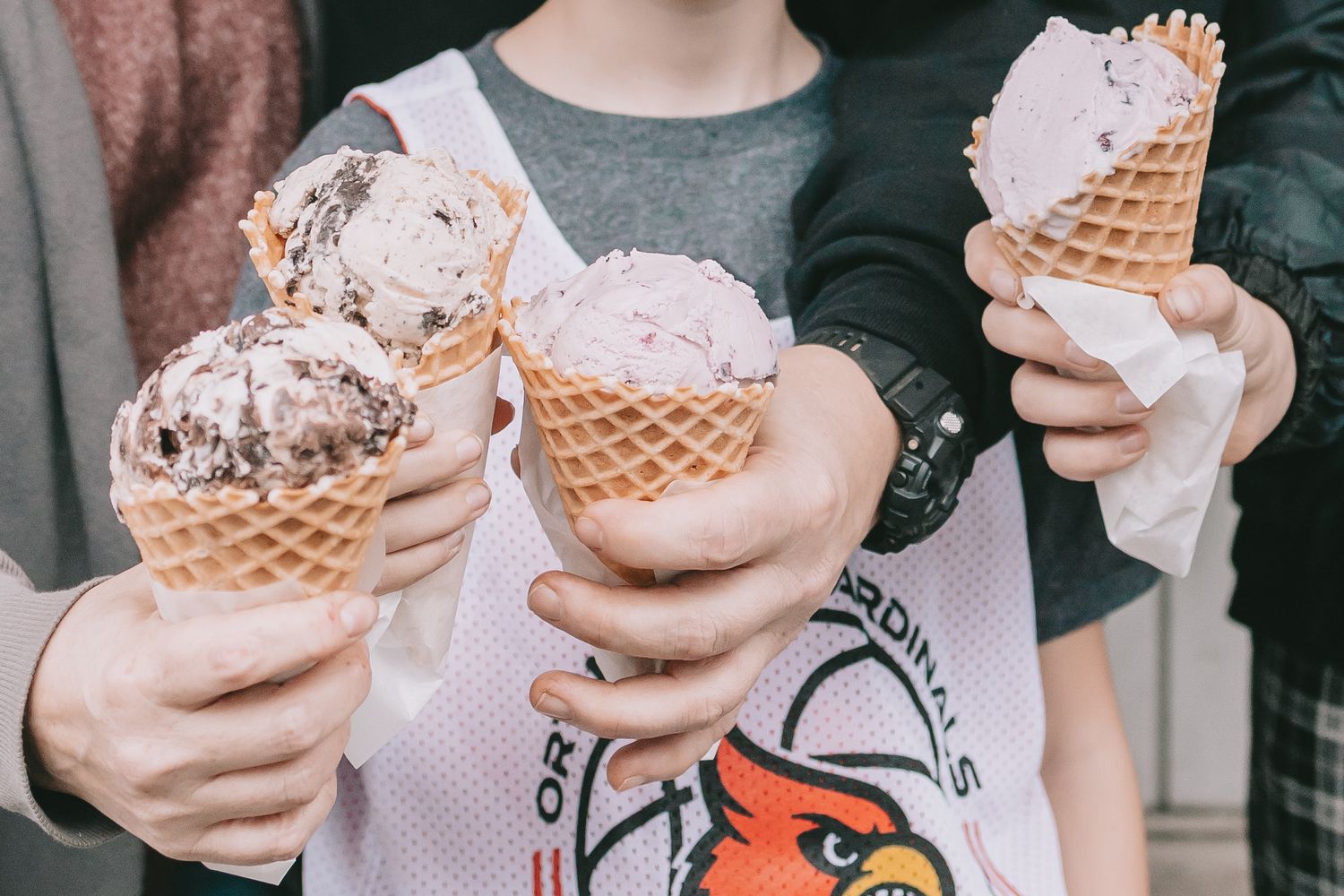 4 ice cream cones held together by 4 hands.