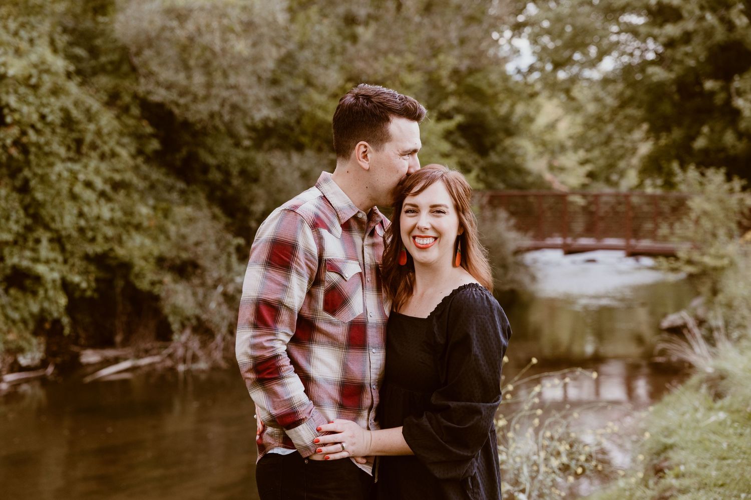 Romantic outdoor portrait by a river with matching casual outfits.