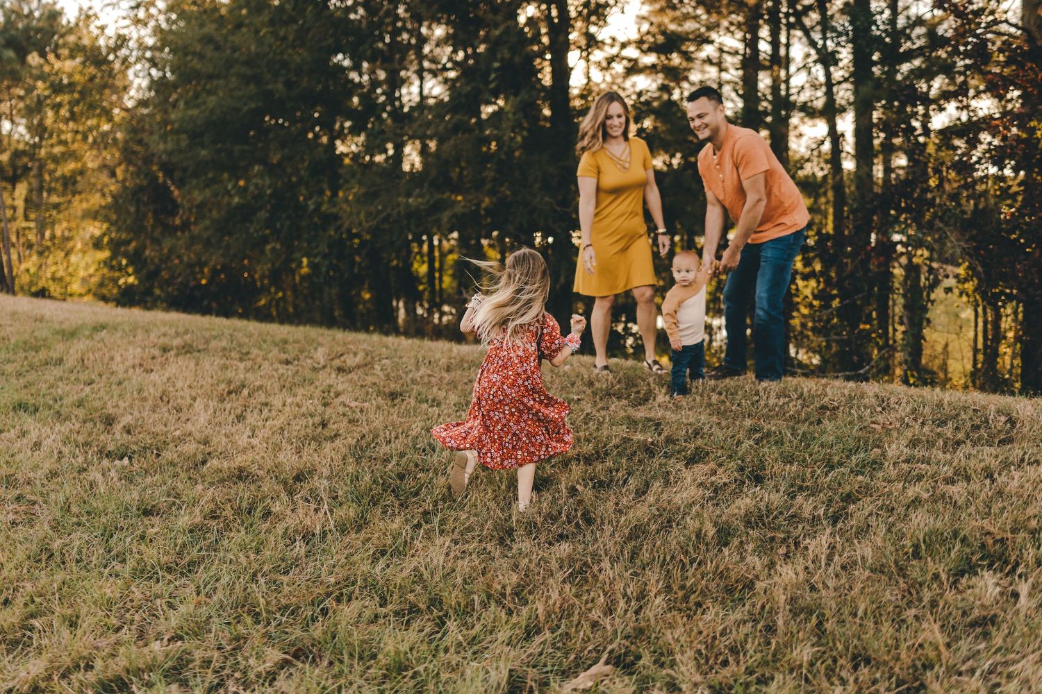 People walking together on a grassy hillside during golden hour.