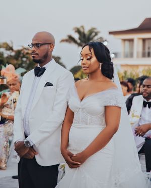 An outdoor wedding ceremony scene with couple in white formal attire.