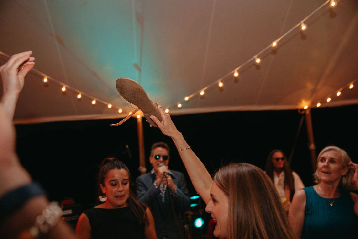 Partygoers dance and celebrate under twinkling lights in a tent venue.