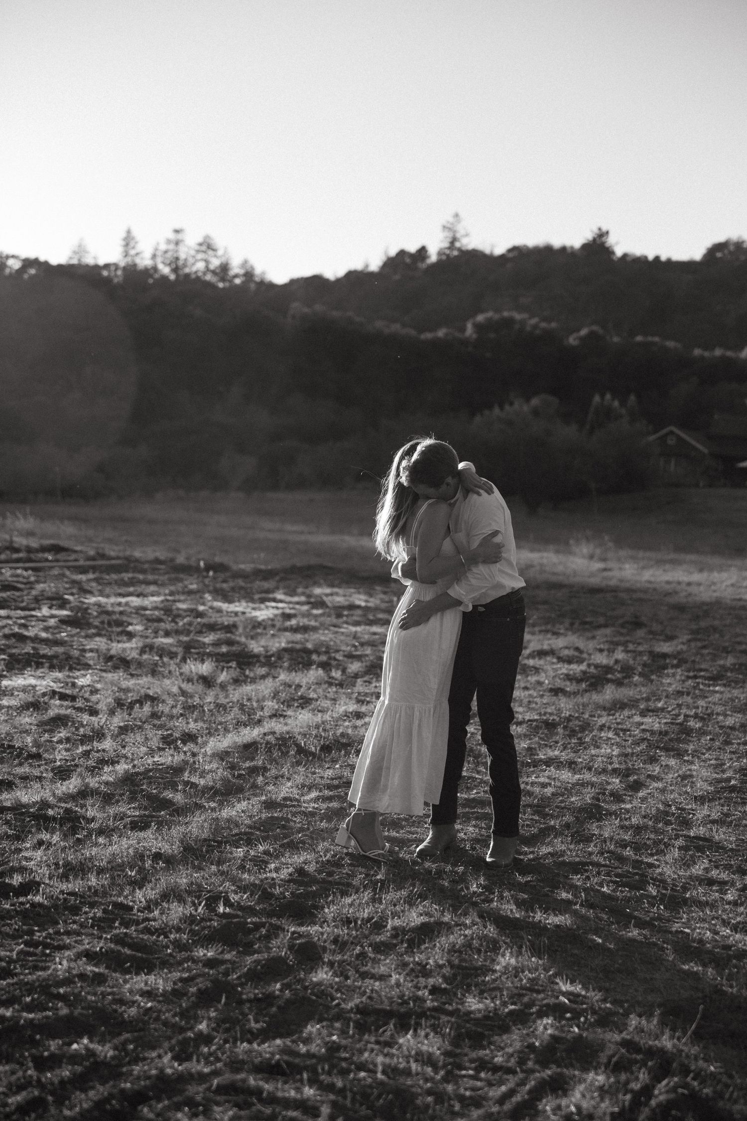 Couple walking hand in hand through a field at sunset.