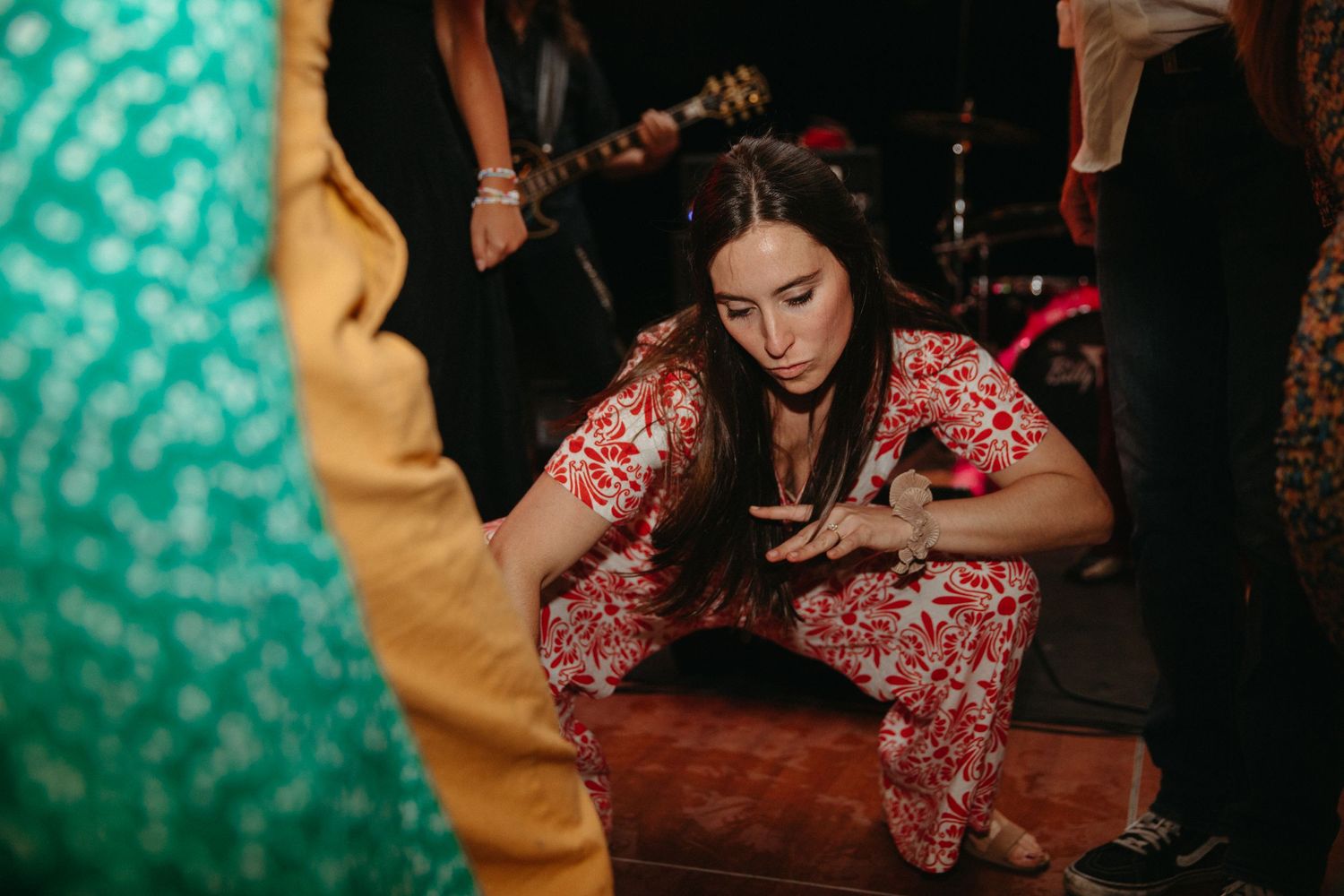 A person in red floral attire dances energetically at a nighttime party.