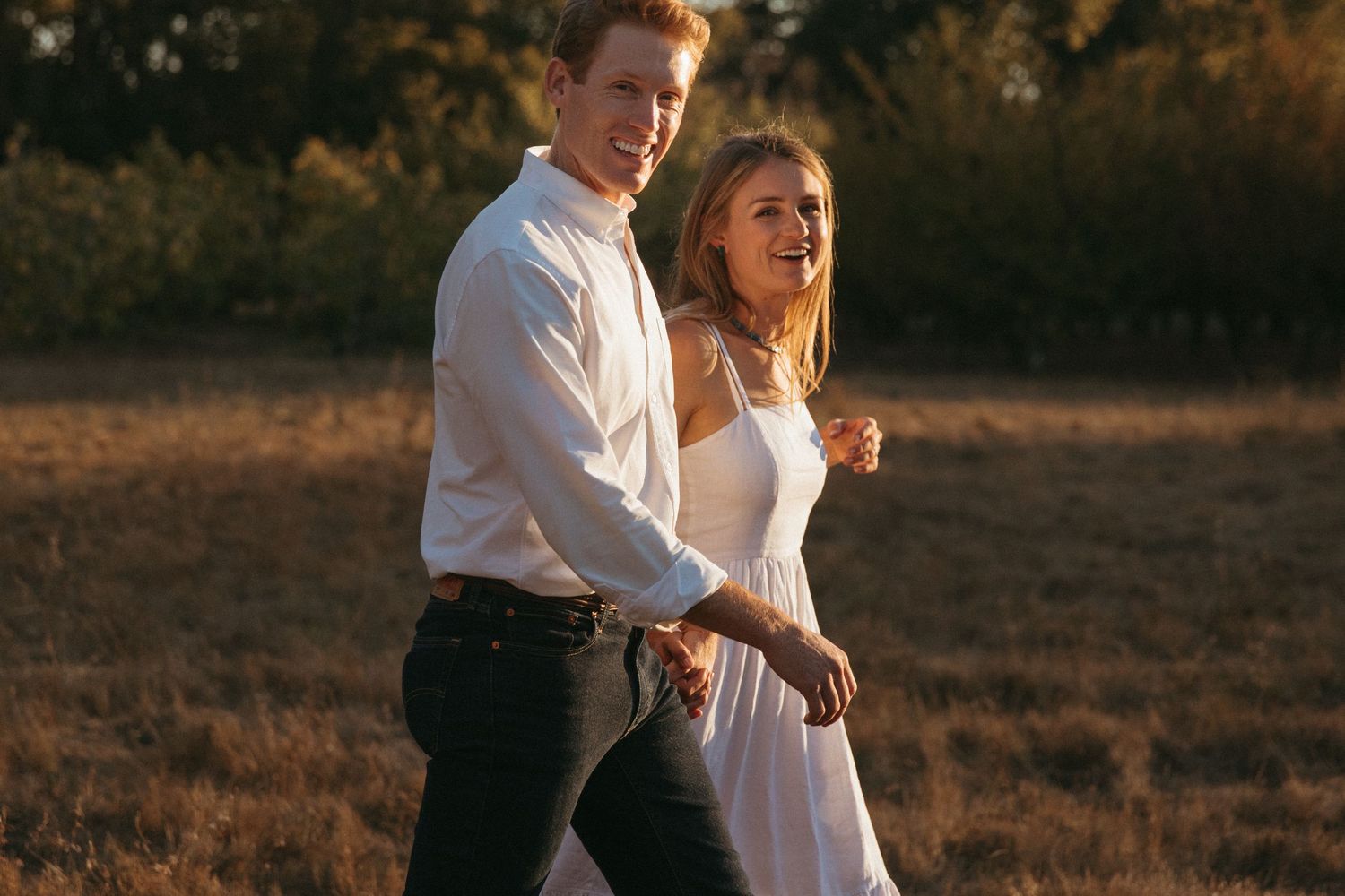 Couple sharing an intimate moment in a sun-drenched field.