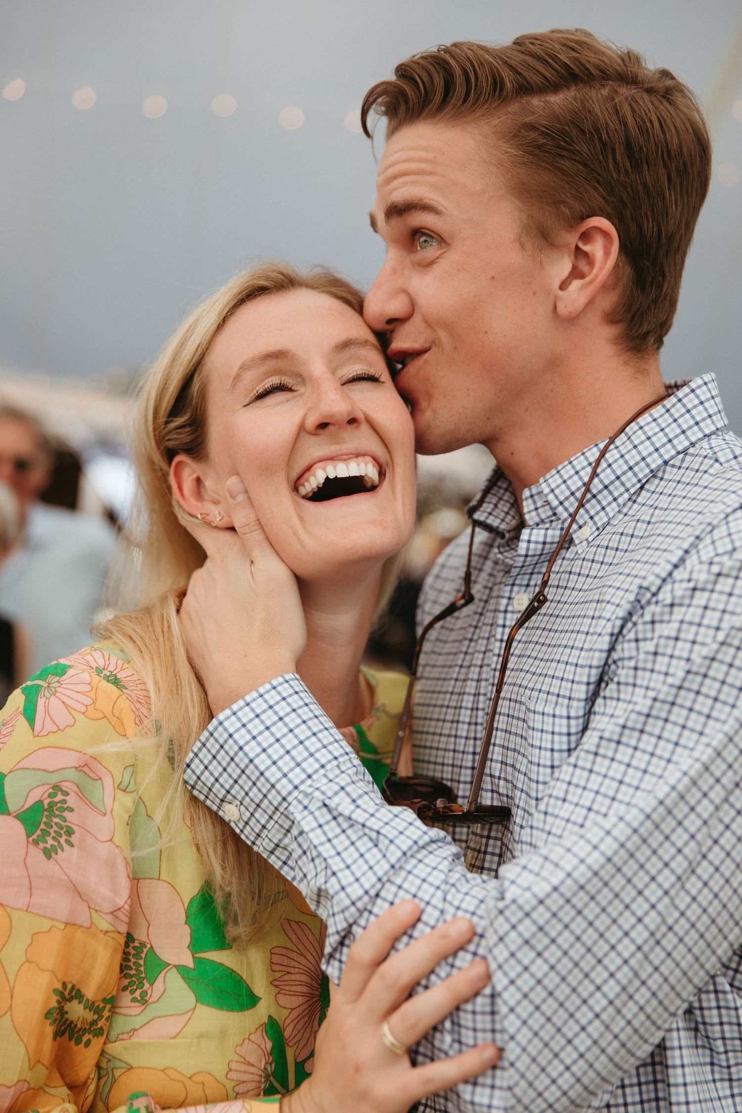 Couple sharing a joyful laugh together at an outdoor celebration.