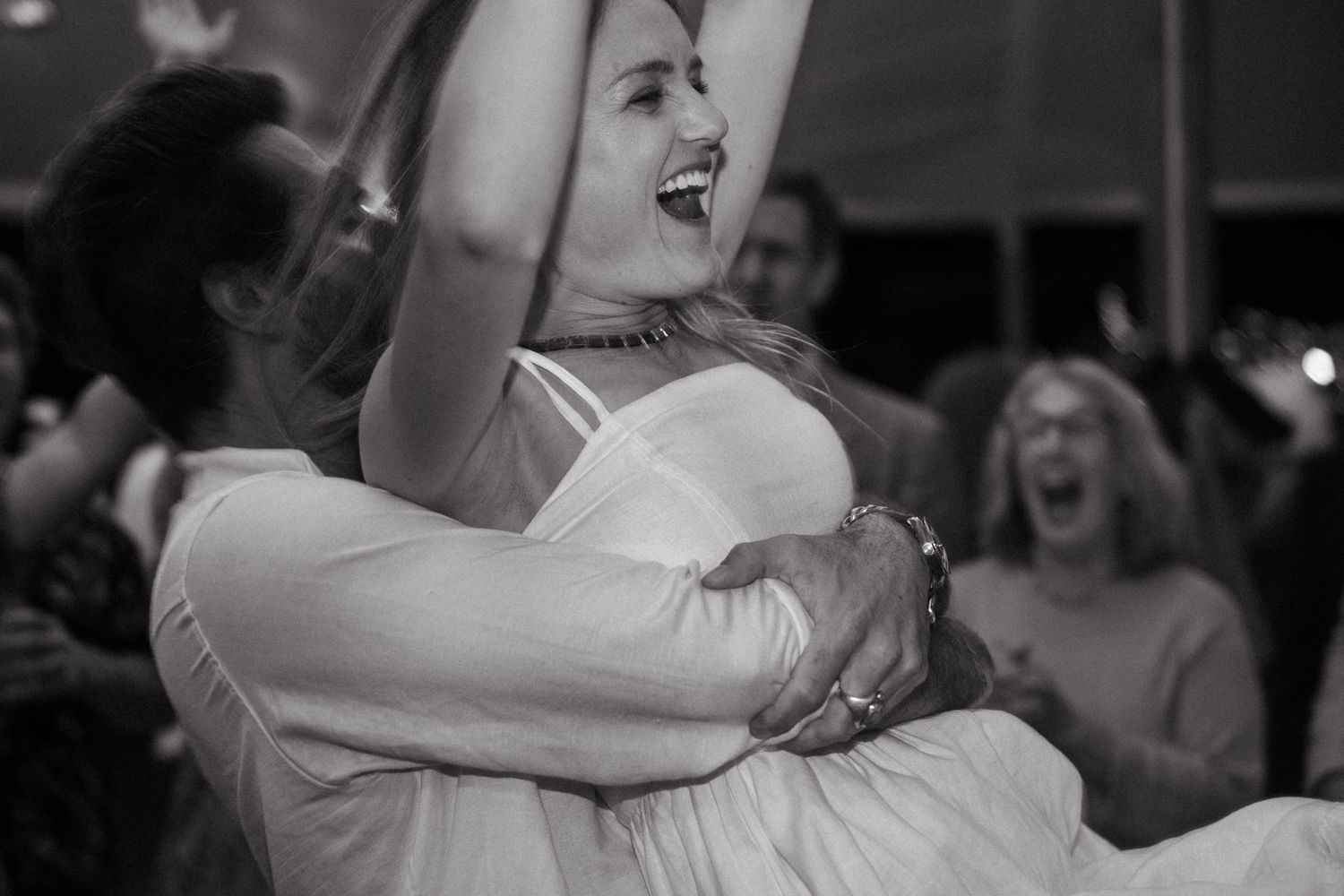 Black and white photo of celebratory dance moments at a wedding reception.