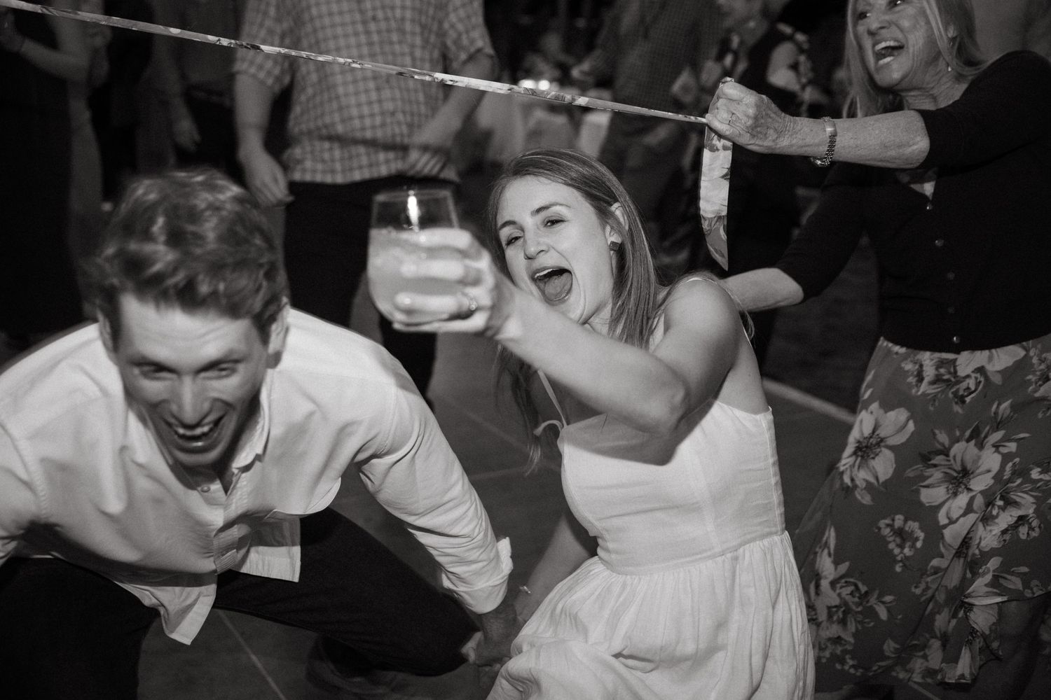 Black and white photo of two people playing limbo at a party.