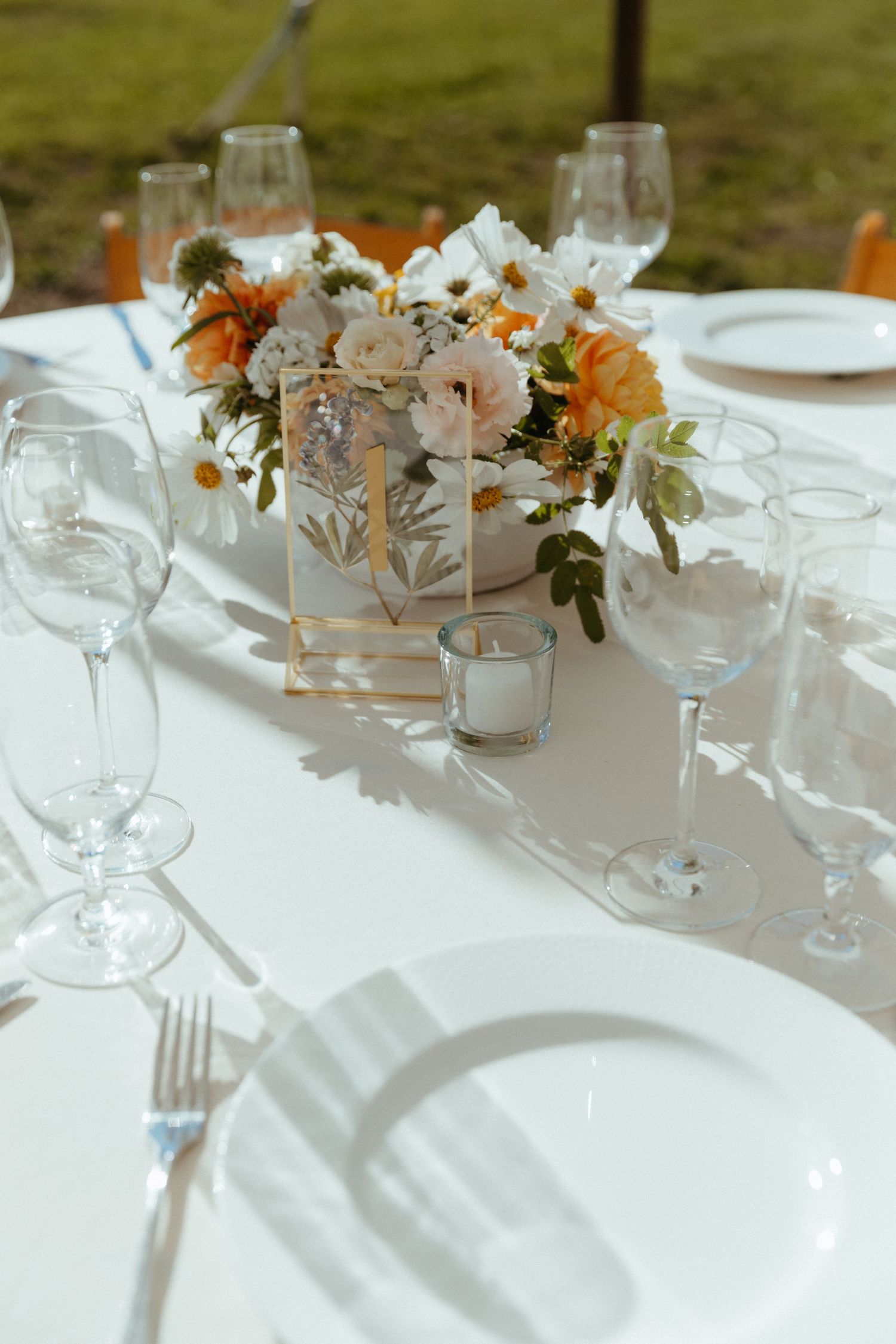 Elegant table setting with white and peach floral centerpiece and crystal glassware.