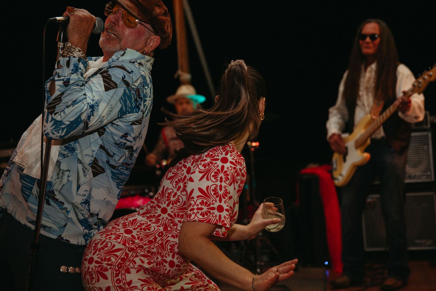 Musicians performing on stage while dancer moves energetically in red dress.
