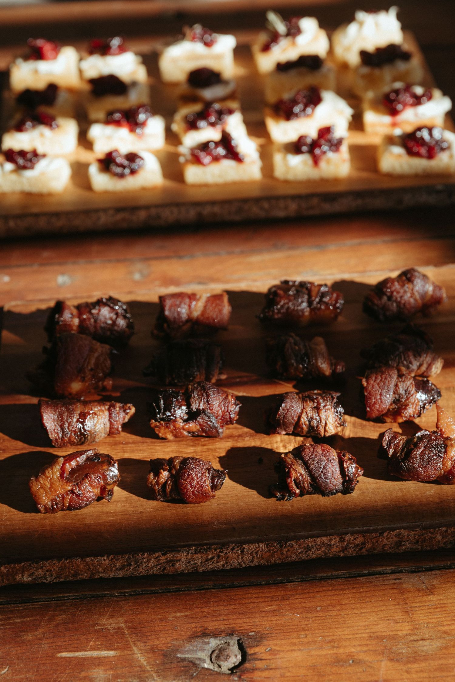 Gourmet appetizers displayed on wooden serving boards featuring meat skewers and cream desserts.