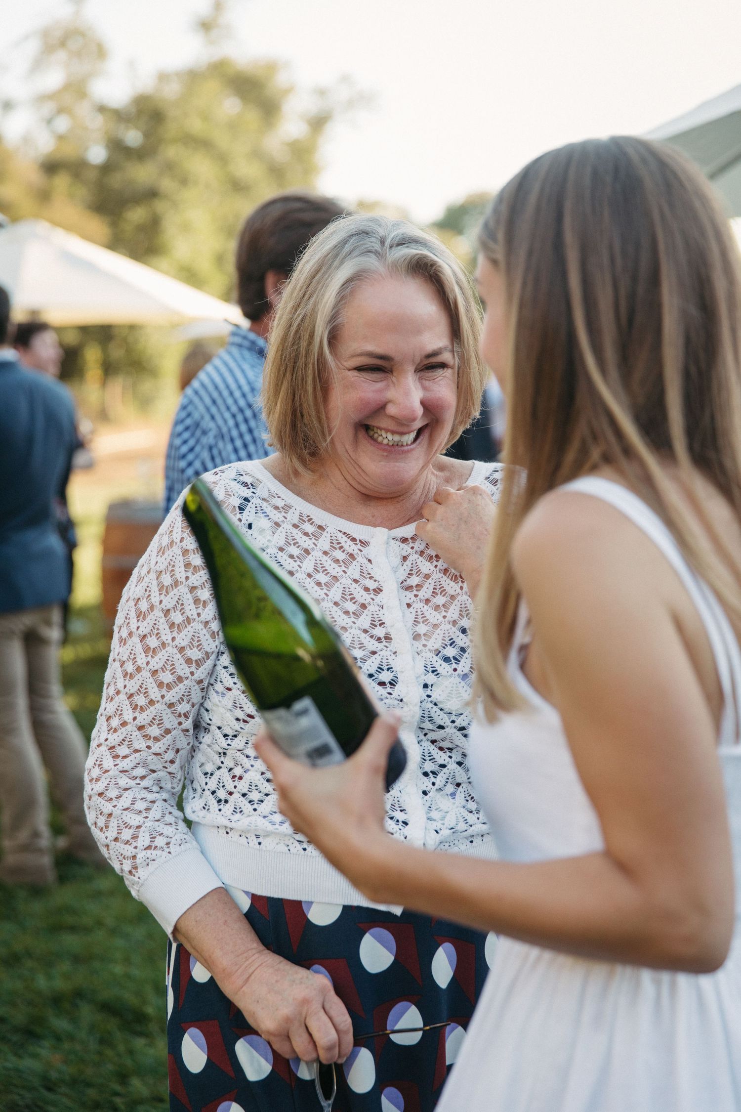 Two guests share a joyful moment with champagne at an outdoor celebration.