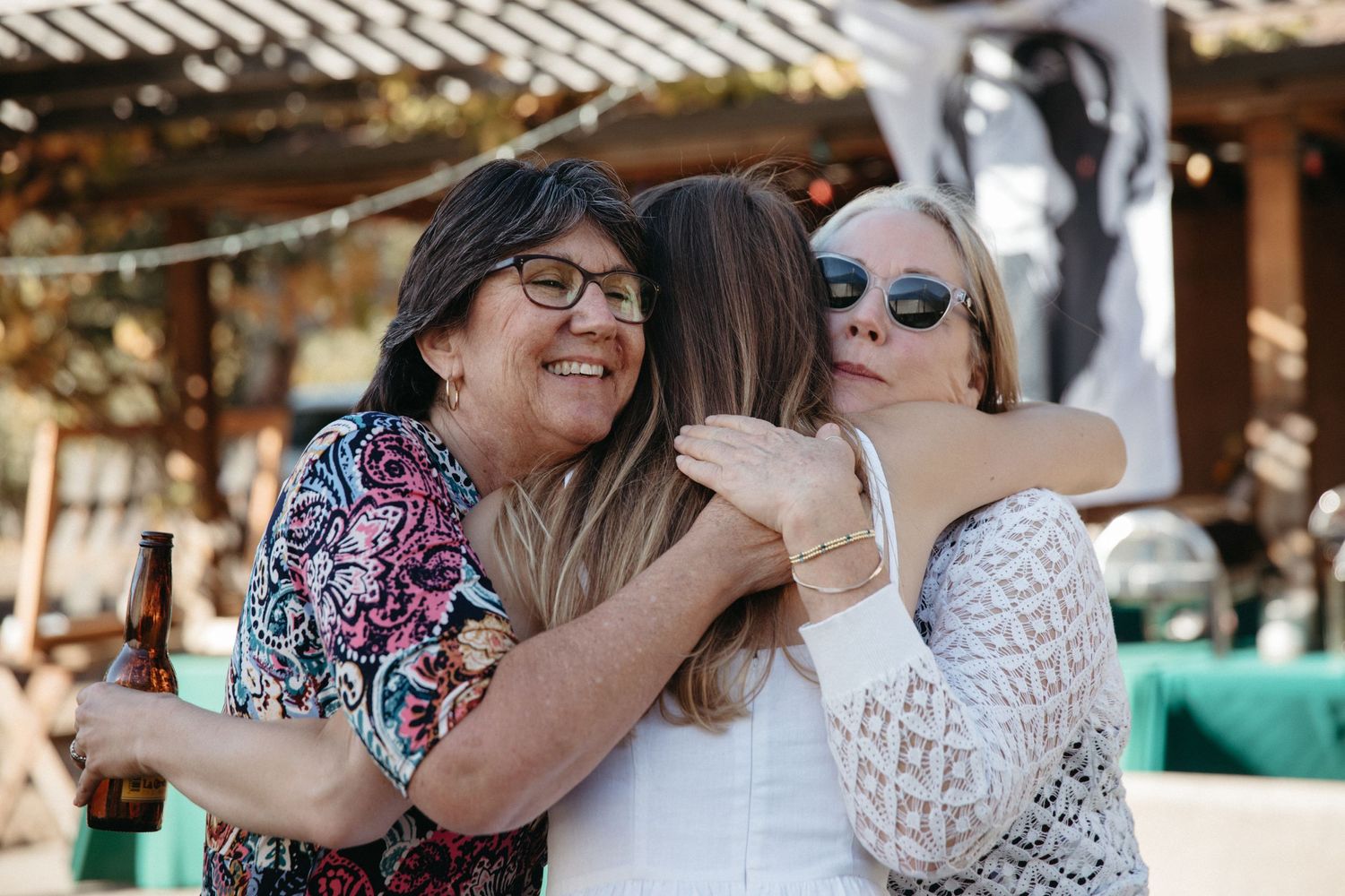 Group sharing a warm embrace and laughing at an outdoor celebration.