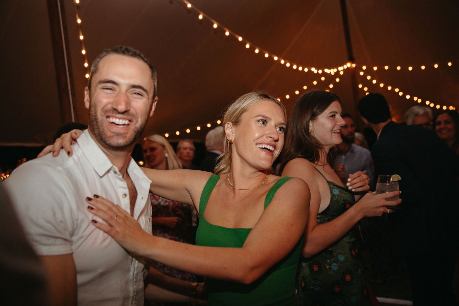 Couples dancing and laughing together at lively wedding reception.