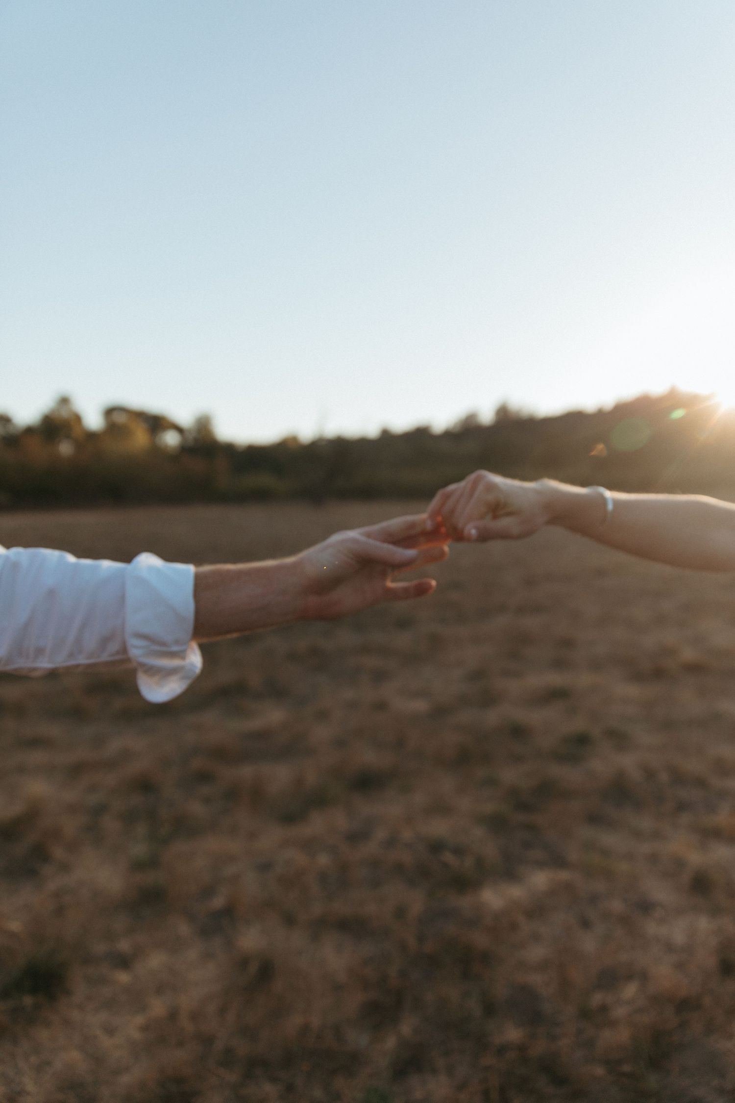 Couple in white dress and button-down shirt posing in autumn orchard.