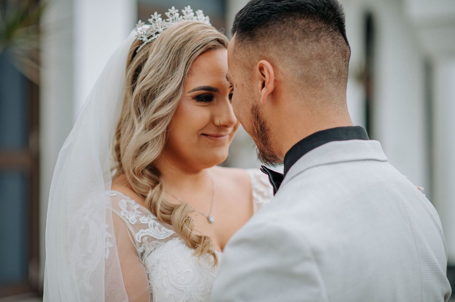 Close up romantic moment between newlyweds under white archways.
