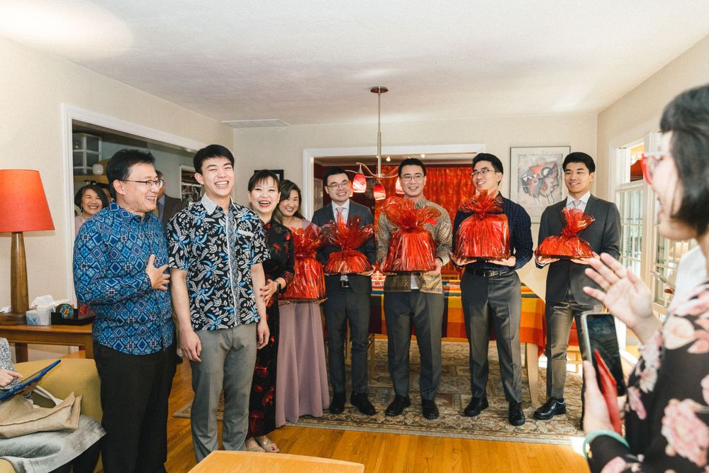 Wedding party members in blue patterned shirts hold red envelopes during ceremony.
