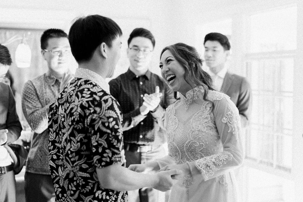 Black and white photo capturing joyful moment during wedding tea ceremony.
