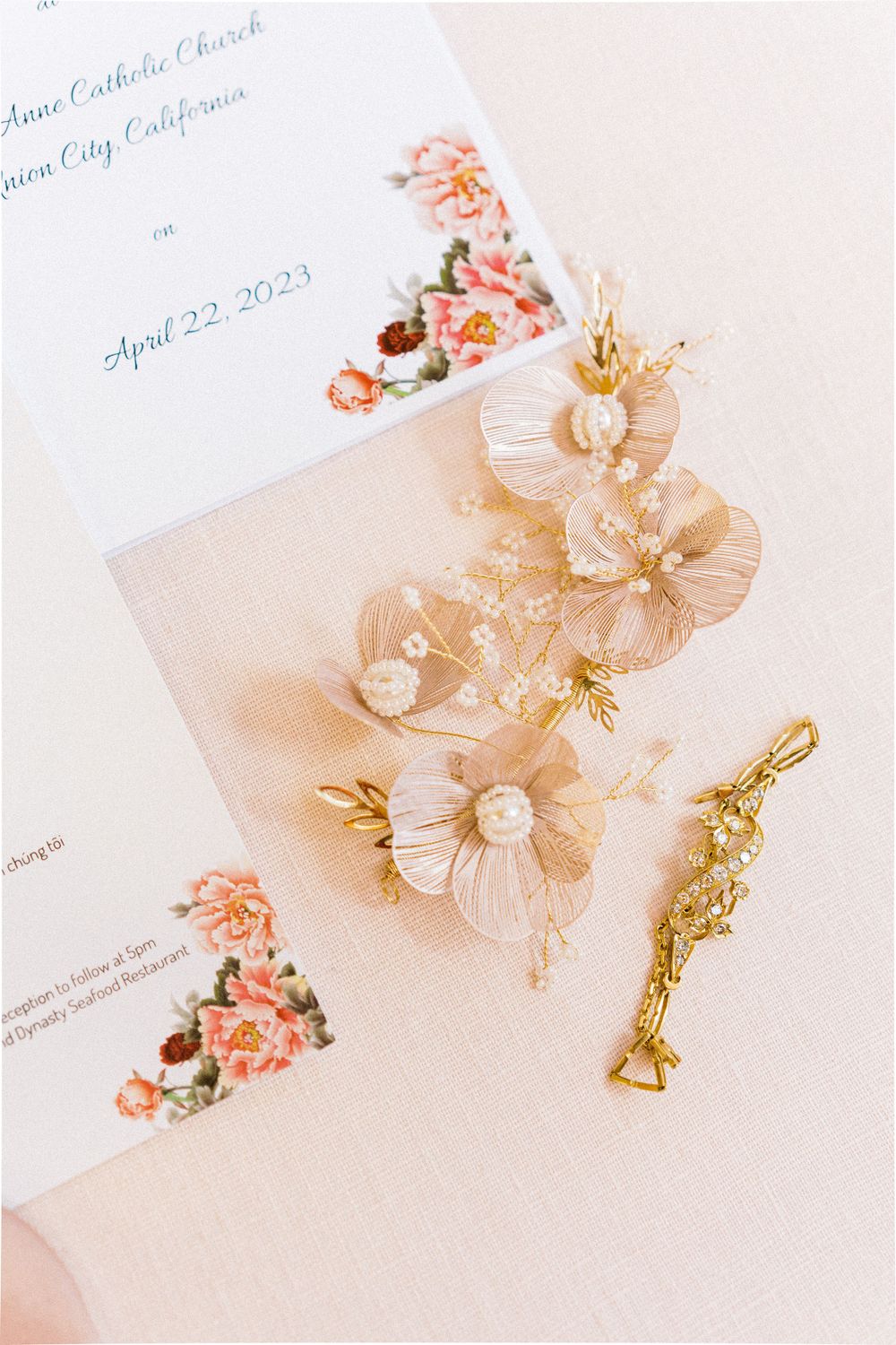 Delicate floral hair accessories and wedding invitation details in soft pink tones.