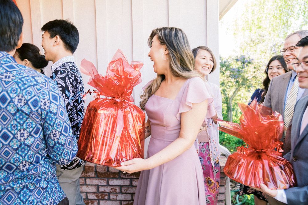 Wedding guests hold red gift packages while gathering at entrance.