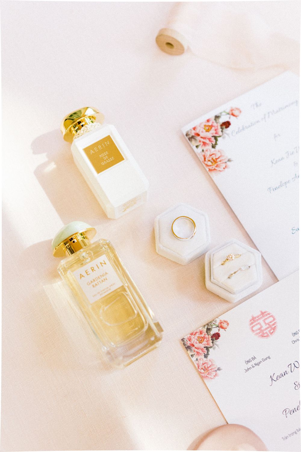 Luxury perfume bottles and wedding stationery with coral floral details.