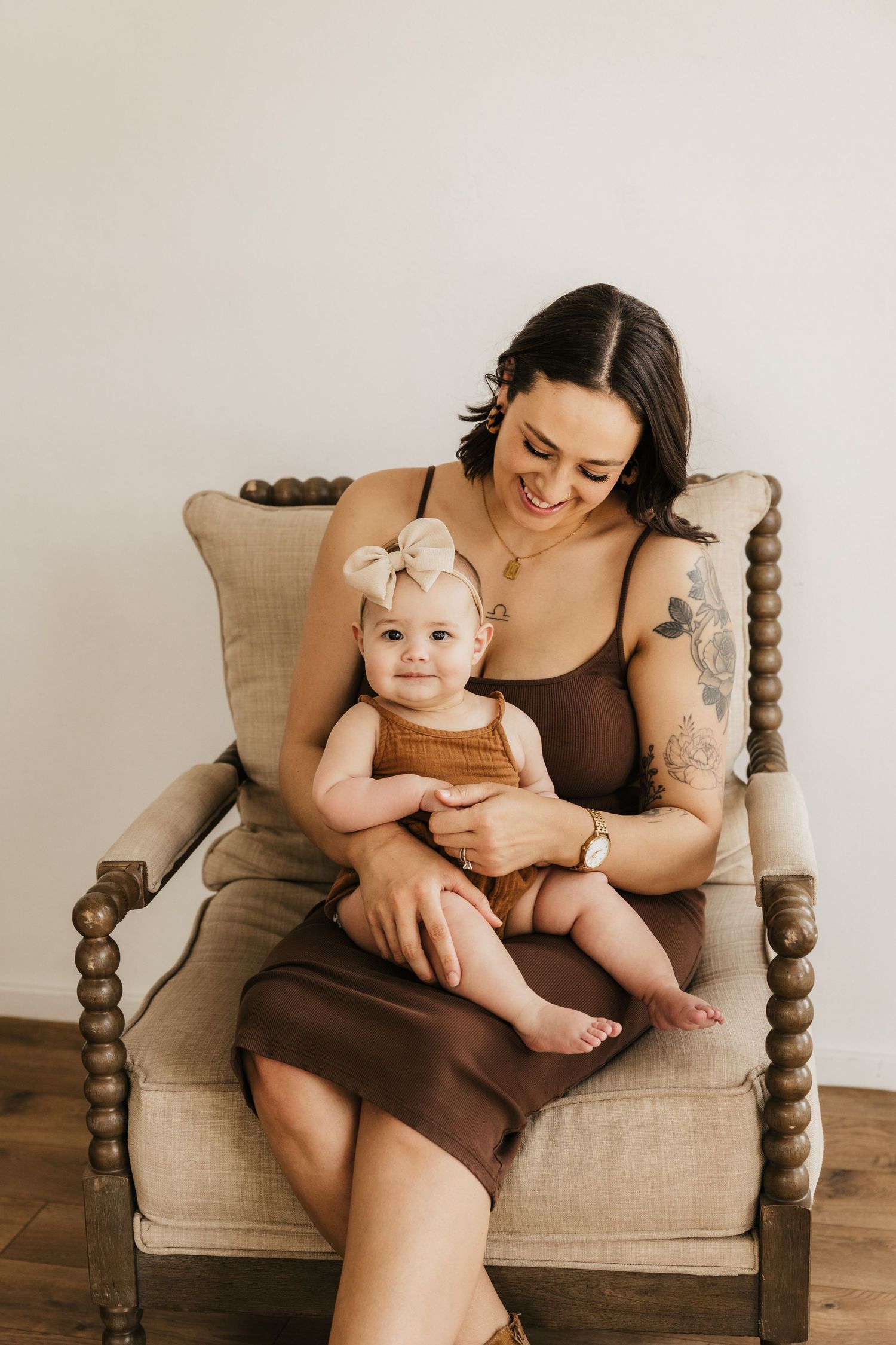 Intimate portrait of mother and baby sitting in vintage armchair with linen cushions.
