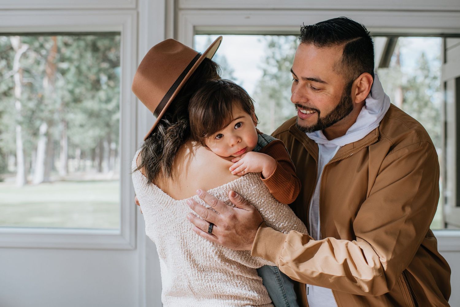 Intimate family moment captured in sunlit room with warm earth tones.