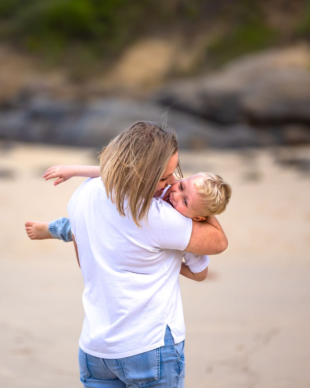 Mother holding her son tight while spinning in circles on the beach