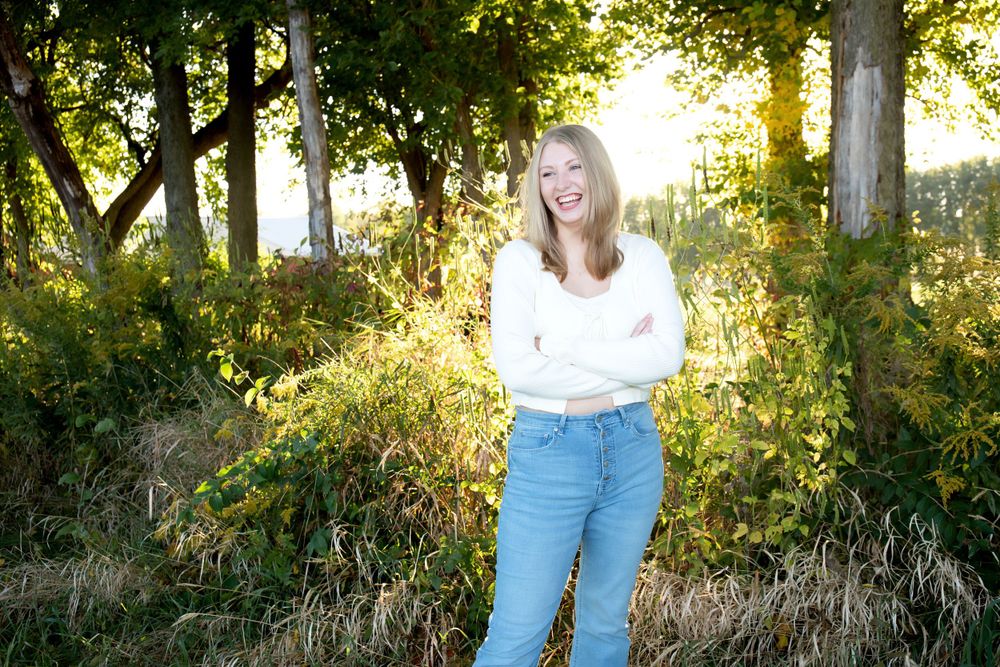 Golden sunlight streams through trees in casual outdoor portrait setting.