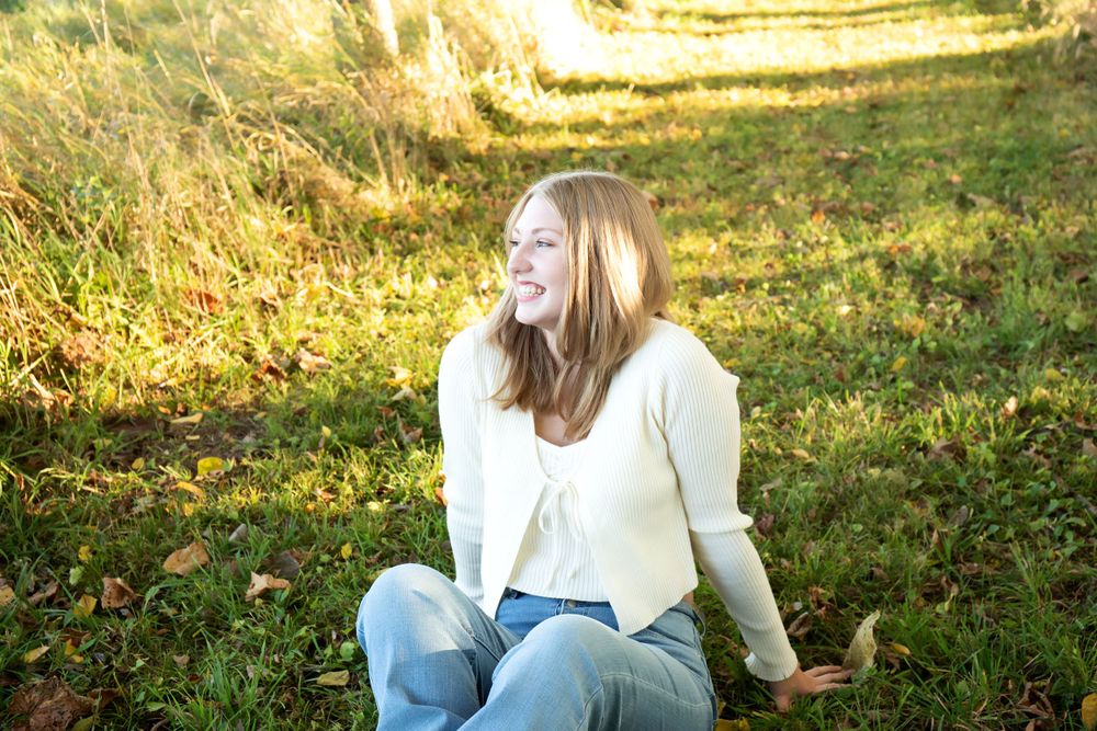 Natural outdoor setting with person seated on grass during golden hour.