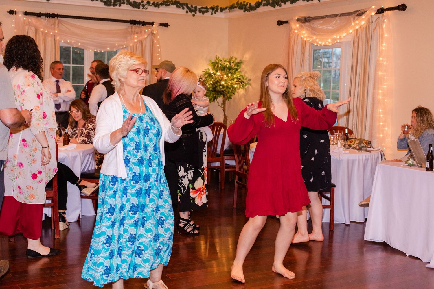 Lively dance floor scene at a wedding reception with guests in colorful attire.