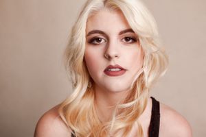 Elegant studio portrait with natural makeup and styled blonde hair.