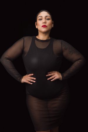 Moody fashion portraits in black sheer outfit against dark background.