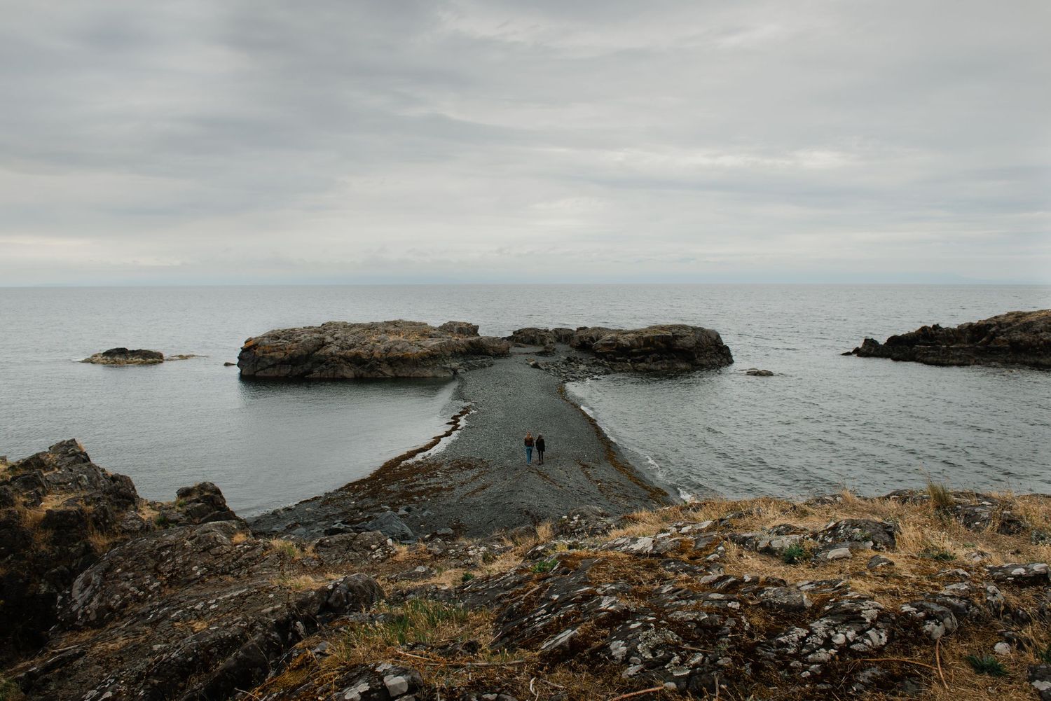Narrow path stretching between rocky cliffs toward a misty ocean horizon.