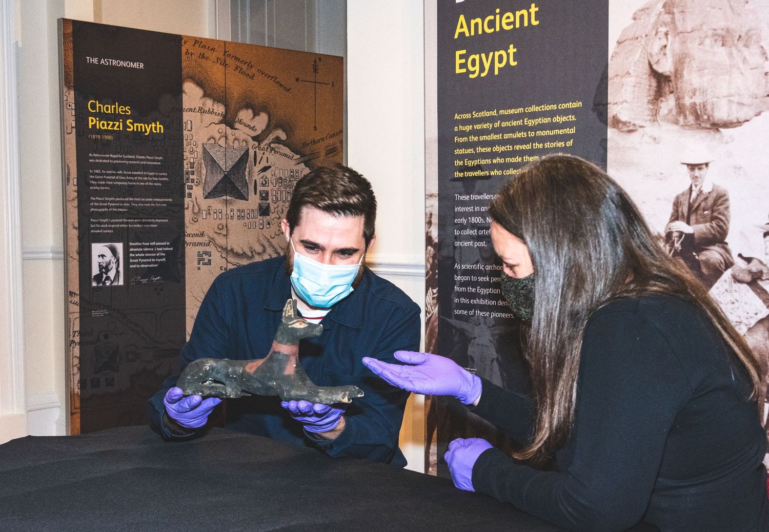 Museum curators examining ancient artifacts at an Egyptian exhibit display.