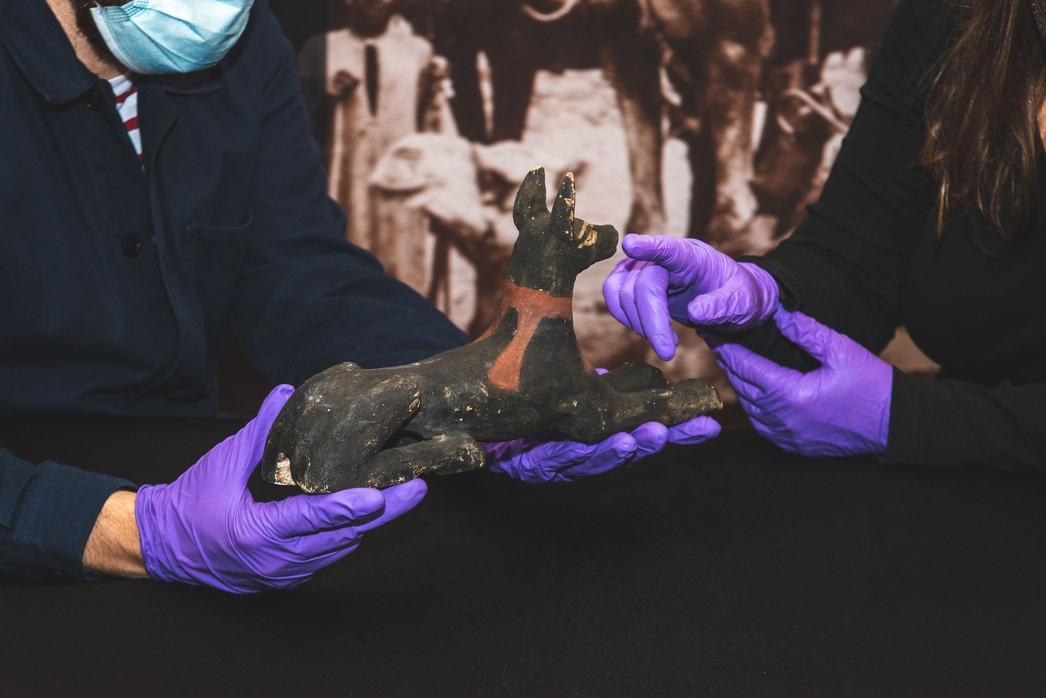 Careful examination of ancient artifacts using purple protective gloves.