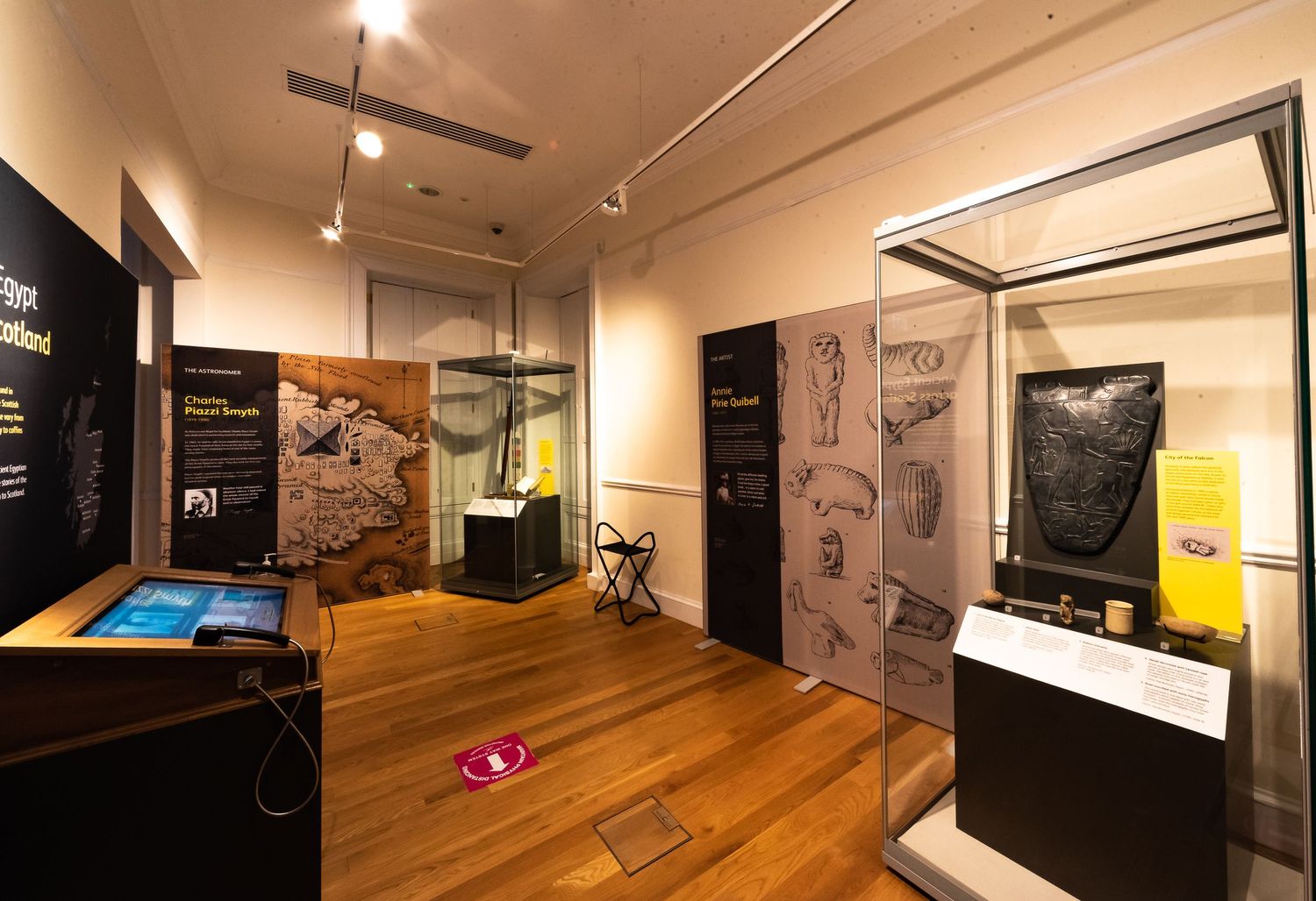 Gallery interior with glass display cases and information panels mounted on beige walls.