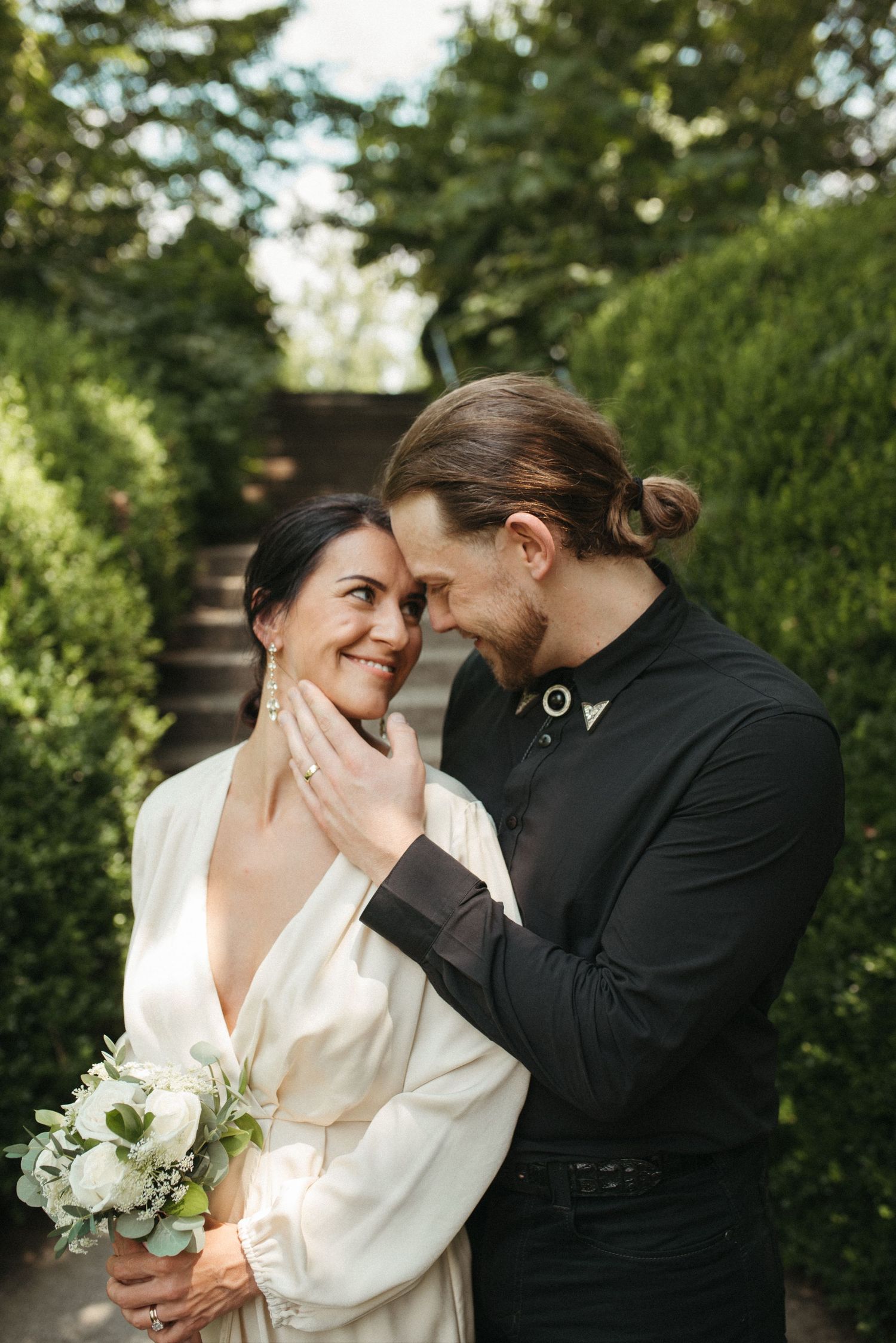 A candid wedding photo of a couple sharing an intimate moment on garden steps.