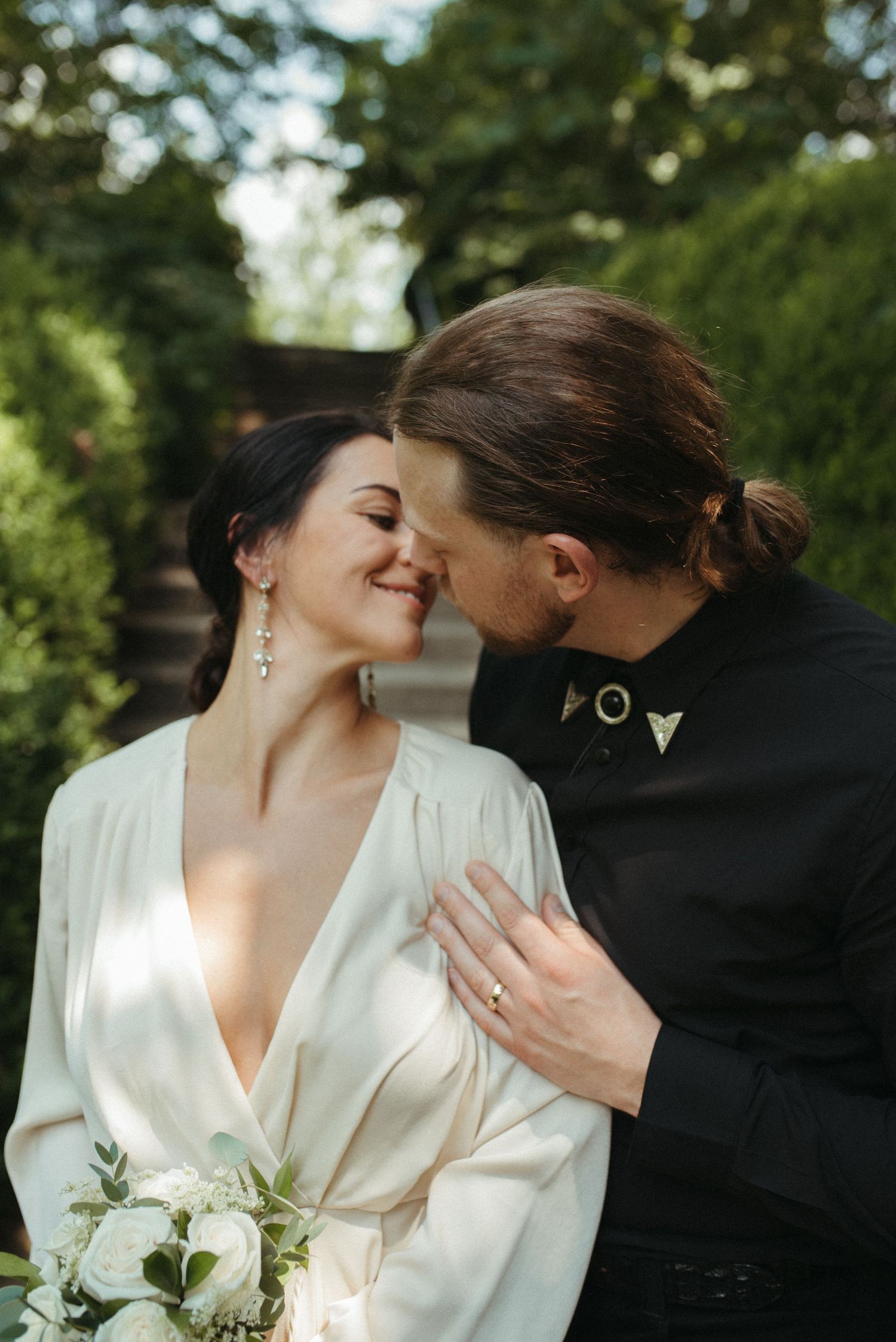 An intimate wedding portrait of a couple in a garden setting with natural sunlight.