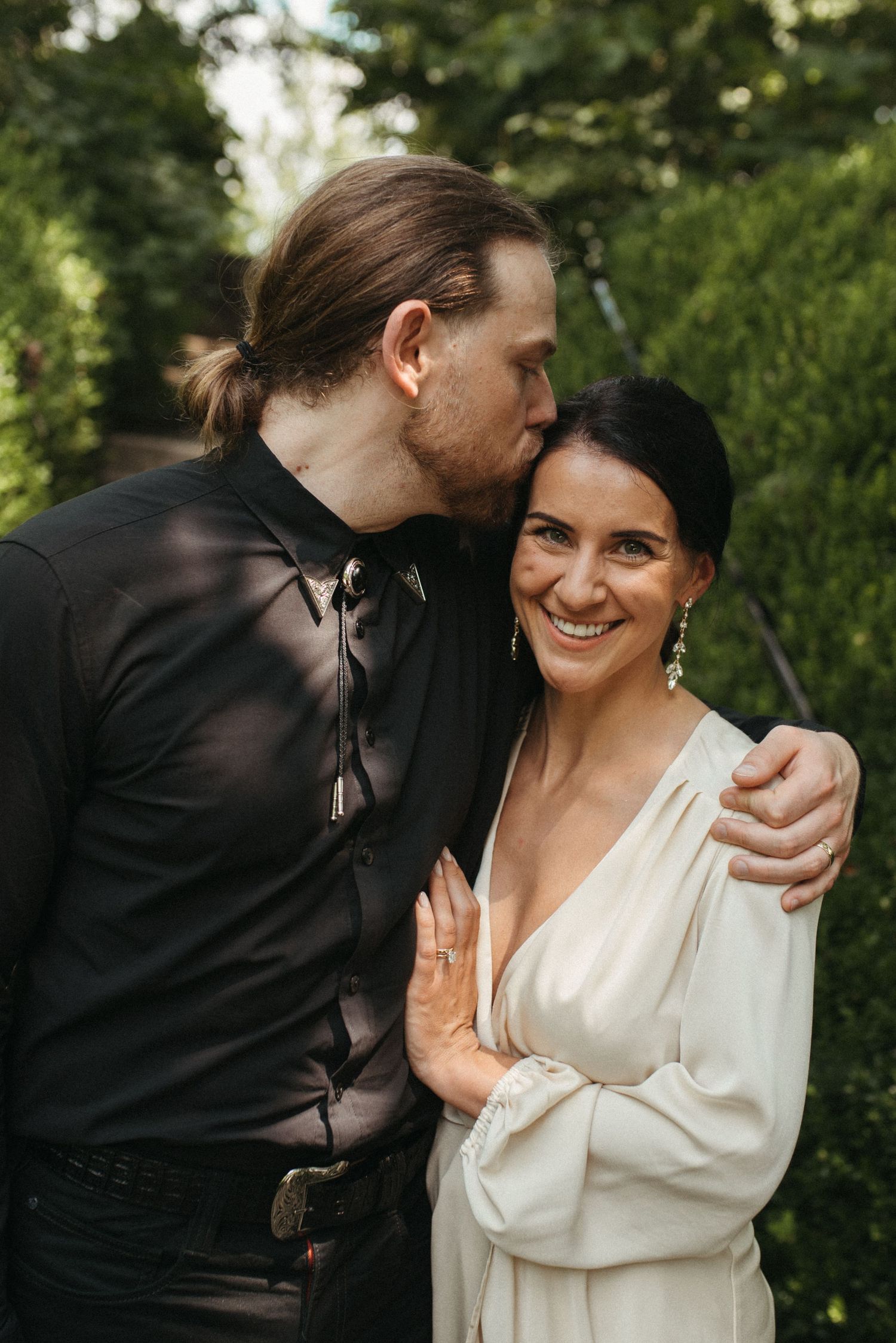 A romantic garden portrait of a couple in contrasting black and white attire.