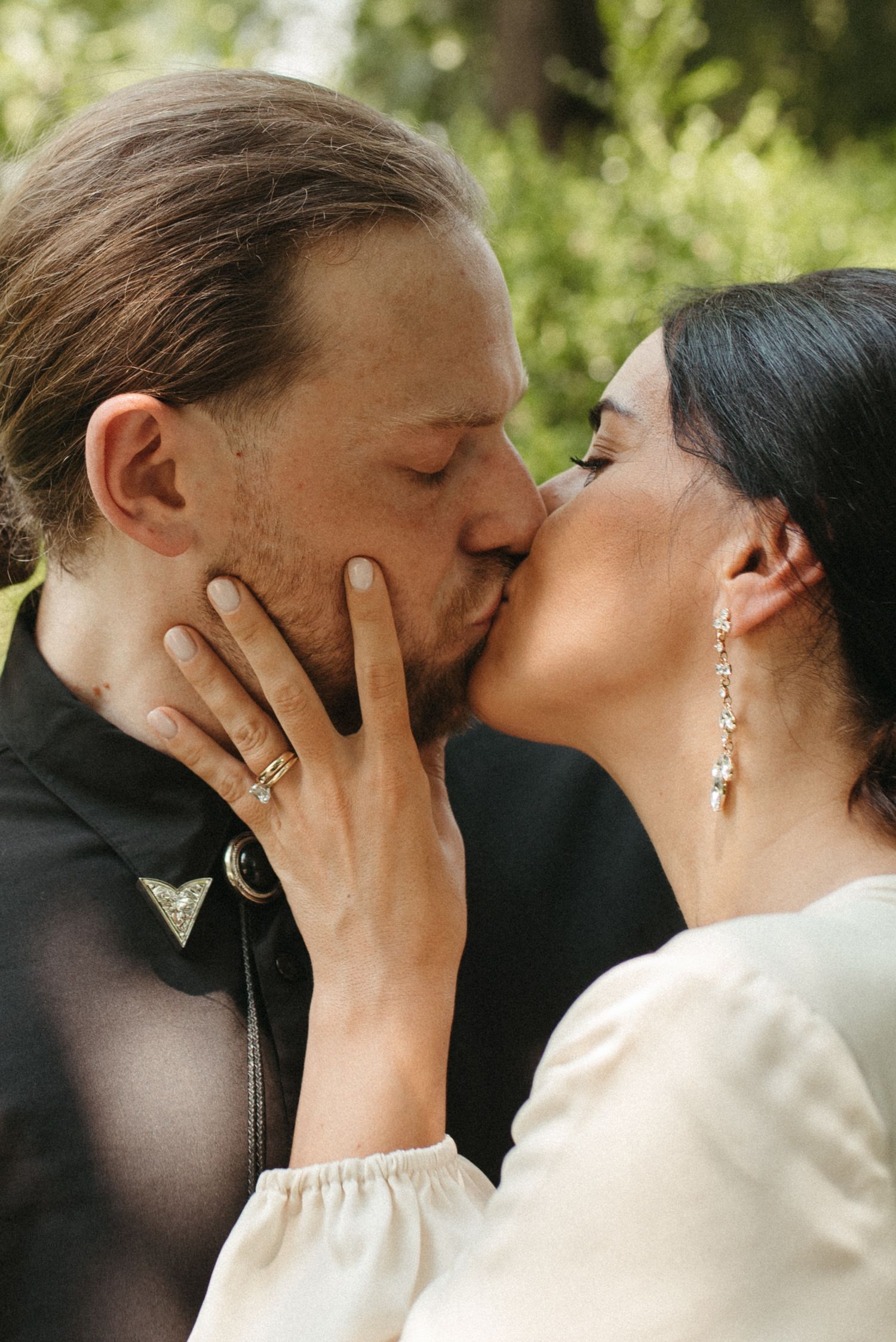 A romantic couple shares a passionate kiss in an outdoor garden setting.