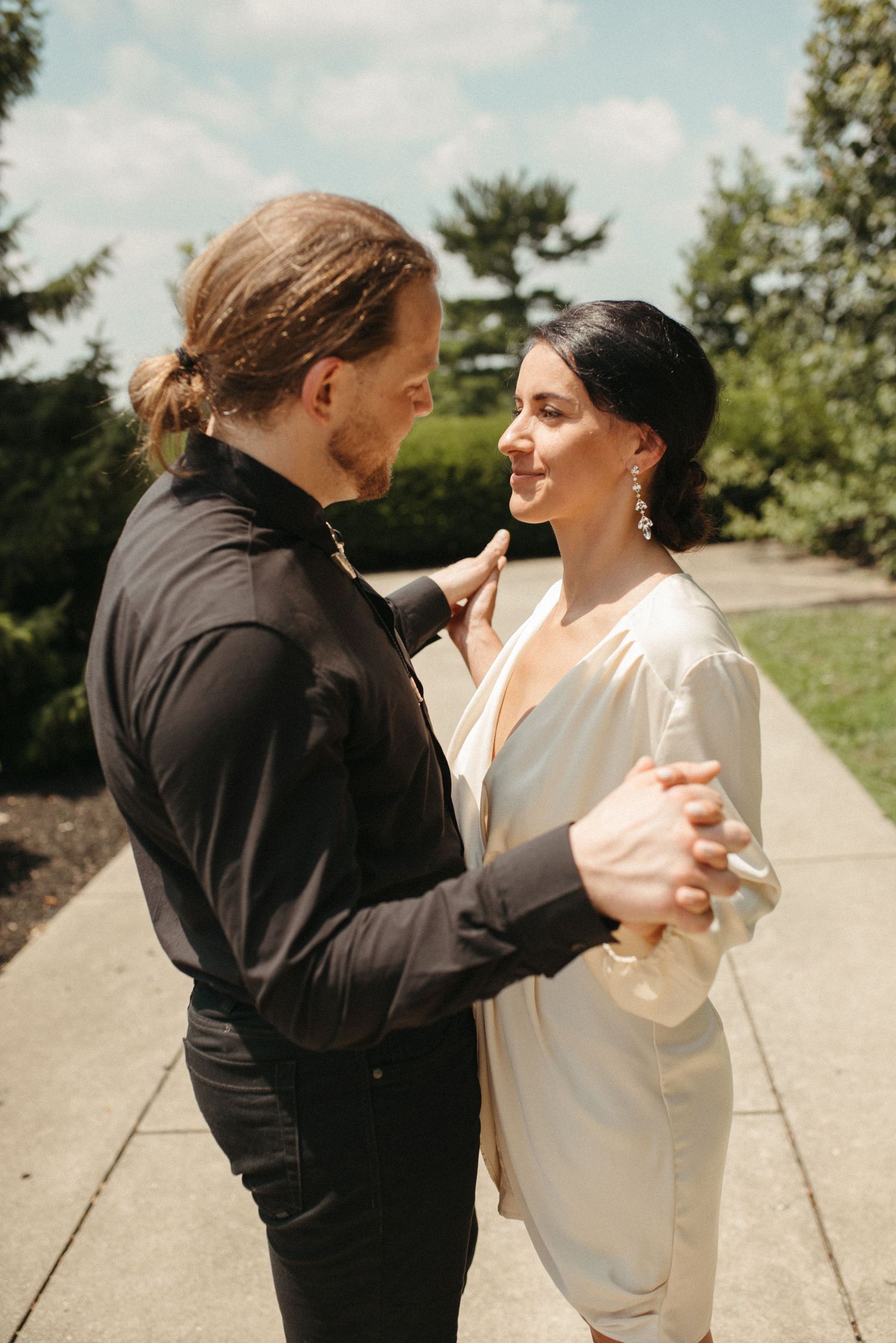 A couple in contrasting black and white outfits share an intimate dance pose outdoors.