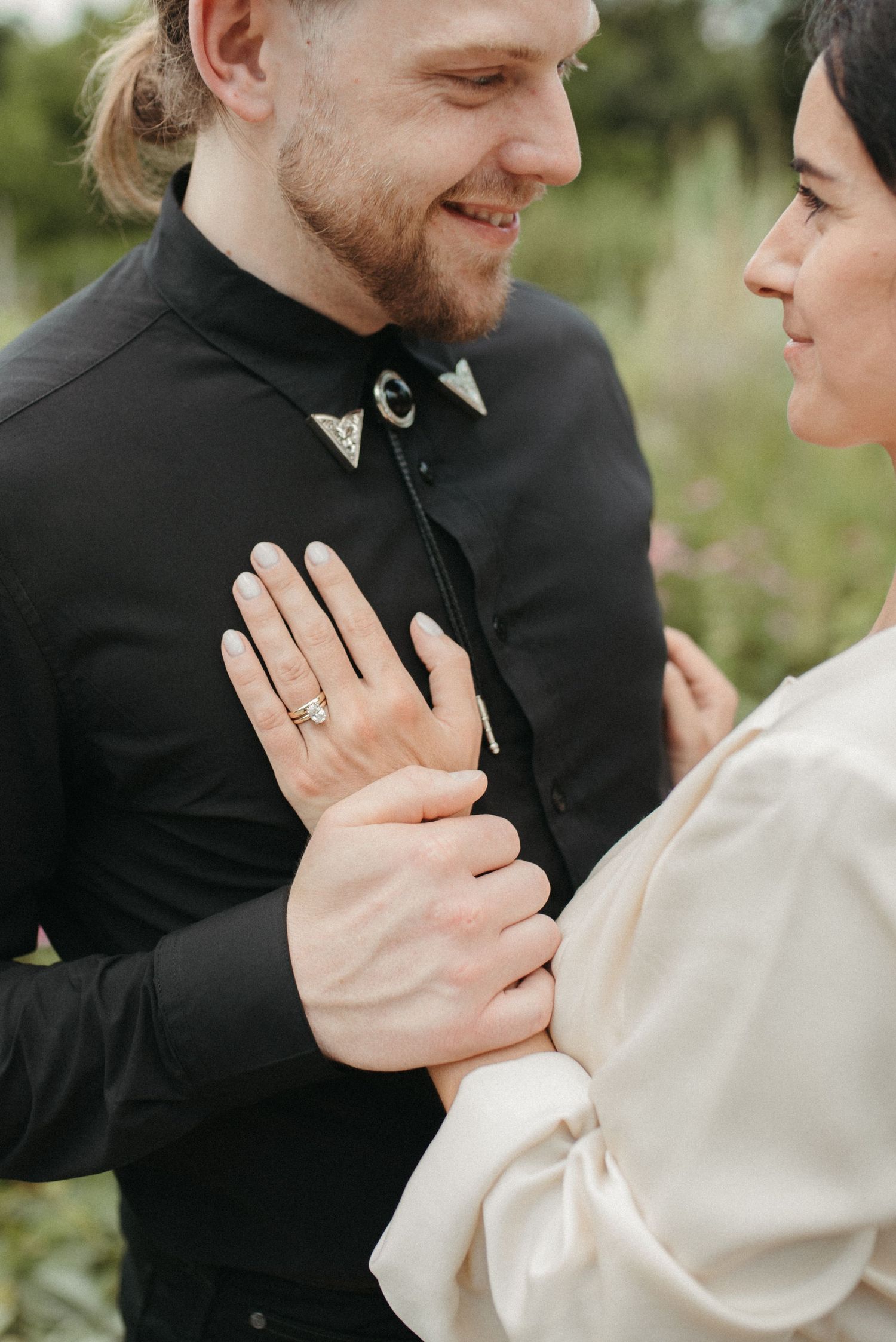 Tender moment captured between couple with engagement ring visible in garden setting.