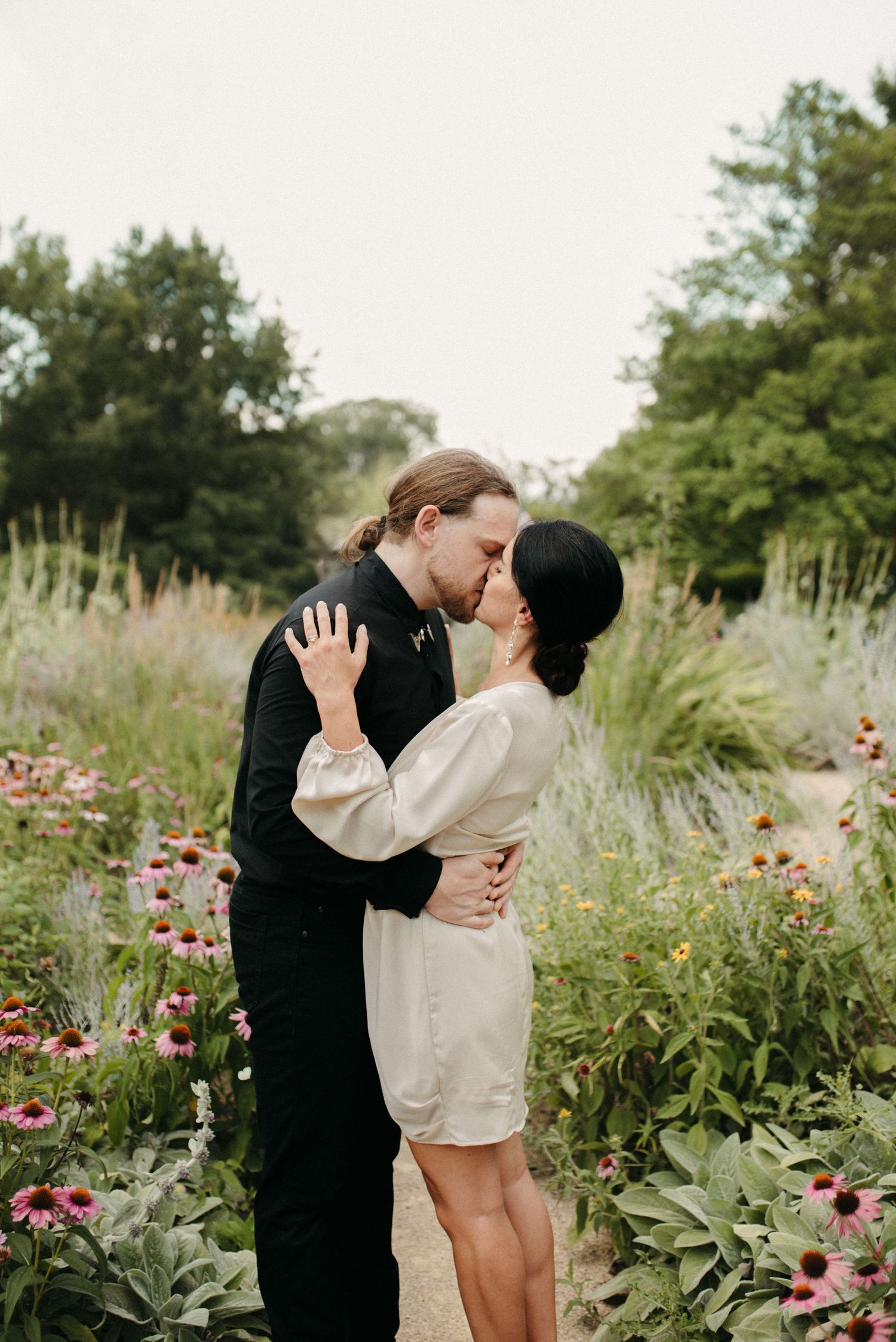 Romantic embrace between couple surrounded by blooming summer garden flowers.