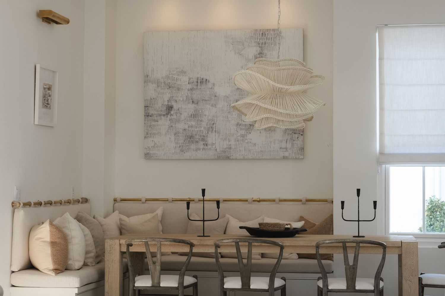 Minimalist white interior with long wooden dining table and modern decor.