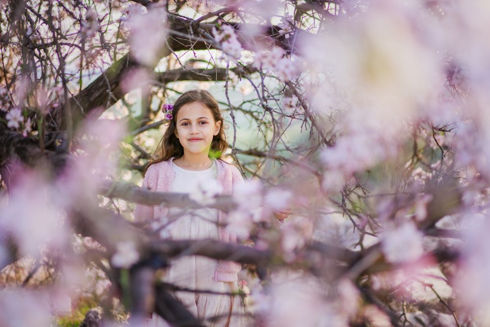 A girl standing inside a pink almond tree
